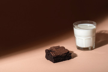Glass of milk and brownie cookie in sunlight. Sweet breakfast