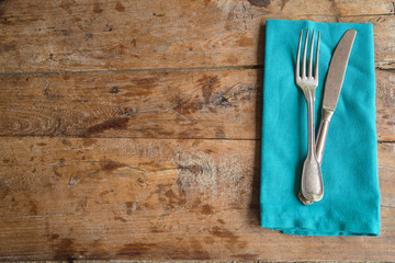 Table setting in retro style. Antique fork and knife on blue napkin and old wooden background....