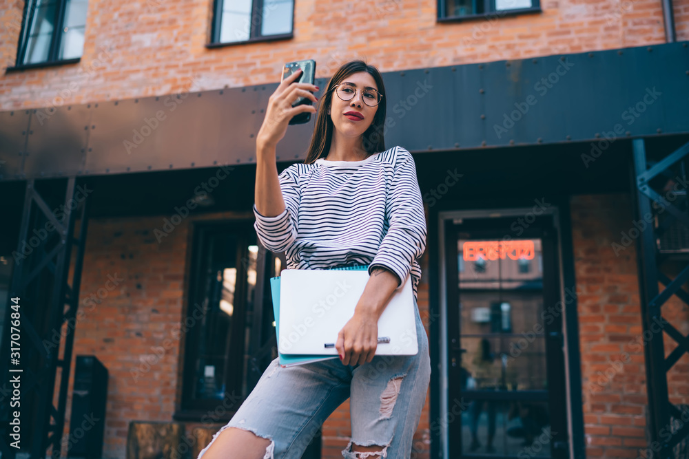 Aufkleber latino student with netbook posing at urban setting for making web selfie content via front smartpho