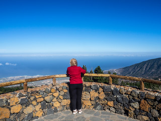 Mujer  con chaqueta rojamirando desde el mirador de la carretera del Teide e en Tenerife