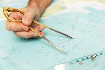 Wandaufkleber The captain measures the distance on the map with a compass. Close-up. © Анна Демидова