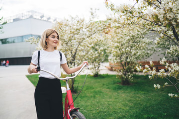 Dreamy content female walking with bicycle in park