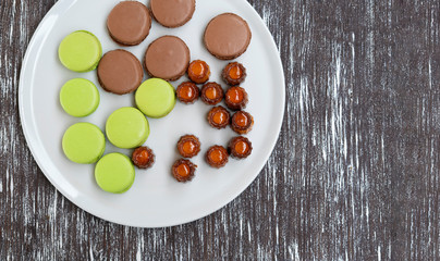 Cookies of pasta, green and brown colors, as well as other sweets, are laid out on a plate.