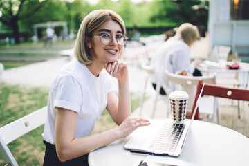 Smart and happy freelancer sitting in street cafe