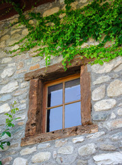 altes Fenster in Bruchsteinmauer mit Efeu