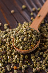green peppercorns in wooden scoop on rustic background