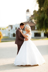 Just married loving hipster couple in wedding dress and suit on green field in a forest at sunset. happy bride and groom walking running and dancing in the summer meadow.