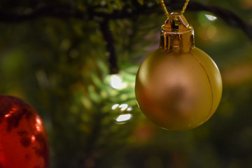 A close up of a red bauble and fairy lights on a christmas tree