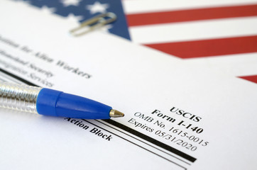I-140 Immigrant petition for alien workers blank form lies on United States flag with blue pen from...