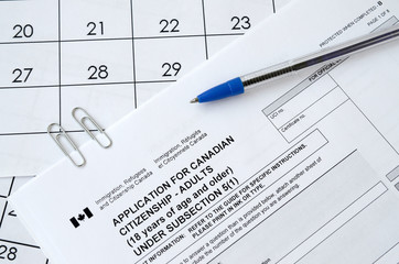 Application for Canadian citizenship for adults and blue pen lies on calendar page