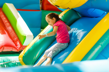 Fototapeta na wymiar Little Girl sliding down an inflatable Slide