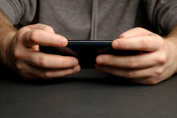 Close up of a man using mobile smart phone. Smartphone in male hands. Closeup of young man Playing videogames On Mobile phone
