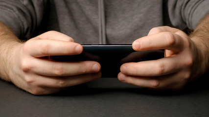 Close up of a man using mobile smart phone. Smartphone in male hands. Closeup of young man Playing videogames On Mobile phone