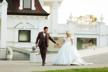 Full length body portrait of young bride and groom running on green grass of golf course, back view. Happy wedding couple walking through golf course, copy space