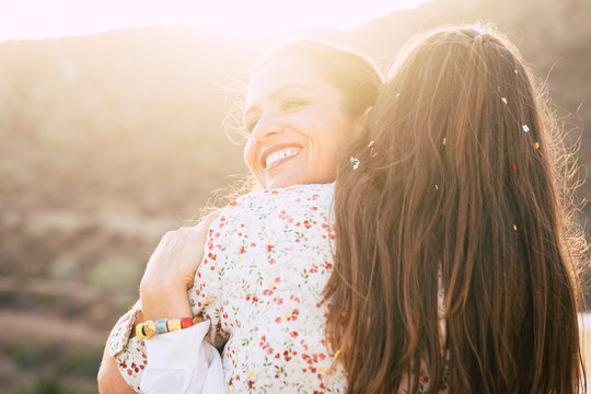 Love and friendship diversity concept - couple of females hug with love and relationship - friends or girlfriends or sisters people hugging - sun in backlight