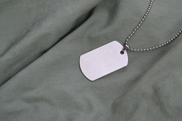 Silvery military beads with dog tag on dark green fatigue uniform