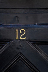 House number 12 on a diagonally carved black wooden front door