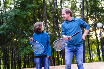 Father teaches son to play badminton in the park. Weekend for two. Parenting concept