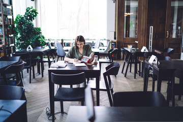 Woman with glasses in hand working on laptop
