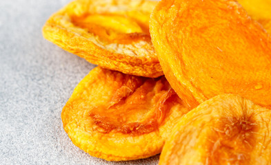 Dried delicious peaches on a gray concrete or stone background. An ingredient for making sweet dishes. Useful fruit. Healthy snack. Selective focus, copy space
