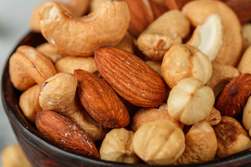 Healthy mix of different nuts in a bowl on a gray concrete or stone background. Almonds, hazelnuts, cashews close up. A Useful snack. Good nutrition. Selective focus