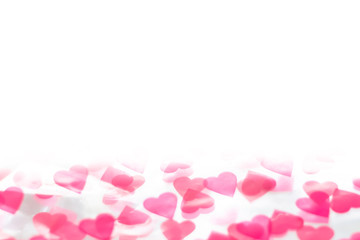 Pink heart shaped confetti on white background. Abstract love, St. Valentine's day backdrop. Copy space, soft focus.