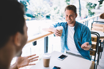 Positive guy chatting with friend in cafe