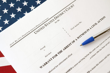 District court warrant for the arrest of a witness in a civil action papers and blue pen on United...