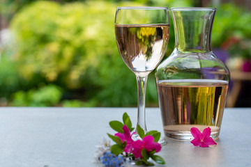 French rose wine served in garden in glass and carafe with colorful spring flowers