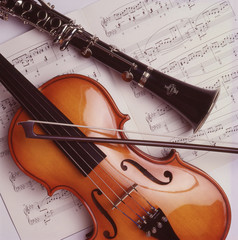 Violon, archet et clarinette noire sur fond de partitions de musique classique