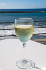 Summer holiday on sea, drinking white wine on outdoor terrace with sea view in sunny day