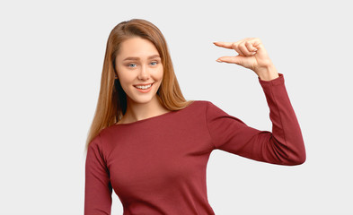 Pretty girl shows gesture little bit. Size concept. Beautiful young woman wears Burgundy-colored...