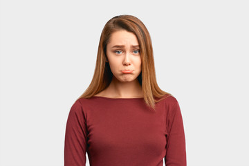 Obraz premium Emotionally wounded woman with sad expression on face, crooked lower lip with disgruntled look. Girl received bad words about work, feels disappointed. isolated on white background in Studio