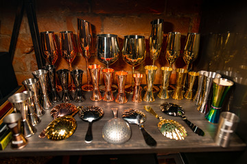 Professional bartender equipment as different metal color jiggers, glasses and strainer spoon