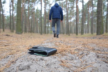 Young man loses his purse with euro money bills on Russian autumn fir wood path. Carelessness and...