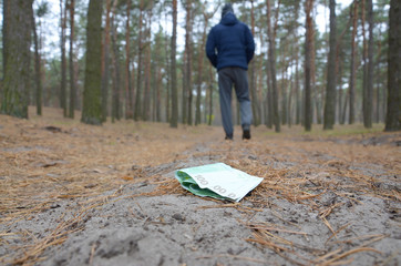 Young man loses his euro money bills on Russian autumn fir wood path. Carelessness and losing money...