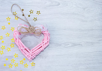 Pink heart on a wooden background. Yellow stars on a light background. The view from the top. Space for text