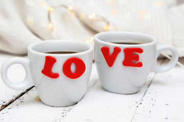 Two cups of coffee with the inscription Love on a painted wooden surface. Concept for valentine's day, wedding day, date
