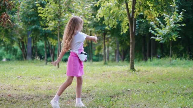 Girl having fun in park. Fashion little girl dancing in green park