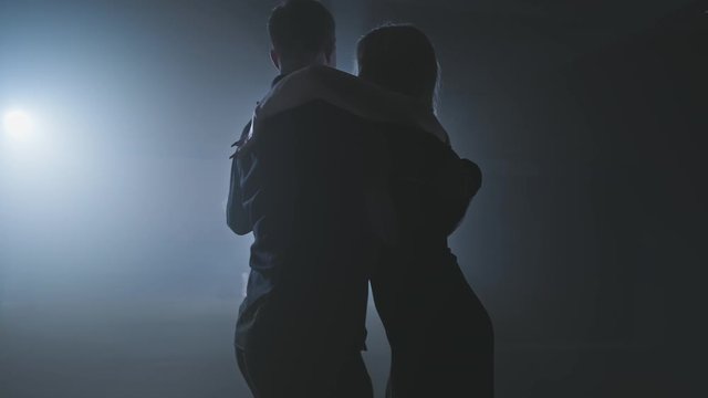 Sensual couple performing artistic and emotional dance. Dance element from tango in slow motion. Smoky studio with lights. Medium shot in 4K, UHD