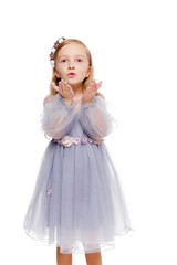 Little fashionable red-haired girl in a gray dress with a wreath on her head blows a kiss