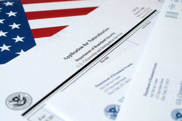 N-400 Application for Naturalization blank form lies on United States flag with envelope from...