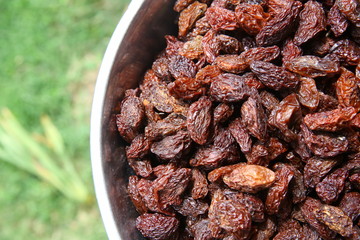 Sweet dry raisins close-up shot for green background . Many Raisins for background grape raisin texture .black raisins in the tray .