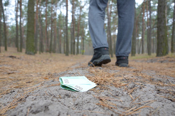Young man loses his euro money bills on Russian autumn fir wood path. Carelessness and losing money...