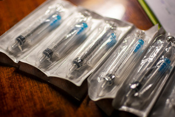 New disposable injection syringes in a package, close-up, selective focus. Syringes on a dark wood background. concept of depression, illness.