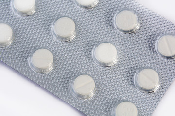 White tablets in blister packs, shallow depth of field. Close-up of medicines, background, concept.