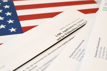 I-589 Application for asylum and for withholding of removal blank form lies on United States flag...