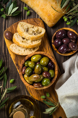 Olives, olive oil and ciabatta on wooden table.