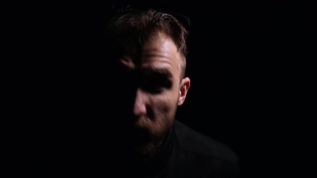 Crazy guy in a dark room. Depressive state of the person. Portrait of an evil and scary guy.