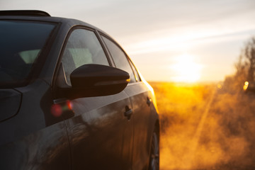 Obraz na płótnie Canvas Close-up of car mirror near road on background of sunrise.